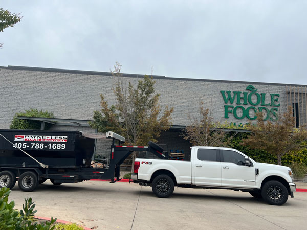 white truck hauling payne-less junk removal rental dumpster outside of a whole foods in oklahoma city
