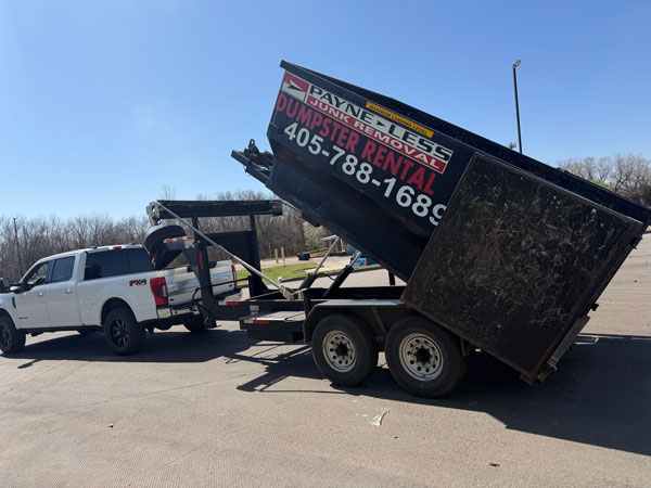 rental dumpster being lifted up on a trailer